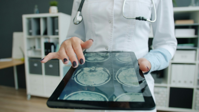 Dokter membahas data pasien di tablet sebagai ilustrasi pemilihan sistem informasi rumah sakit