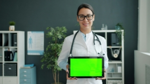 Dokter memegang tablet untuk mengakses data pasien dari sistem informasi rumah sakit