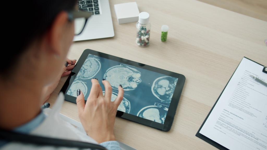 Integrasi SIMRS dengan BPJS dan SATUSEHAT: Panduan untuk Rumah Sakit Dokter memeriksa hasil pemindaian pasien di layar tablet