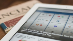 Tablet berisi berita online di atas koran cetak