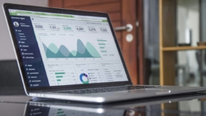 Laptop menampilkan dasbor data di atas meja kaca