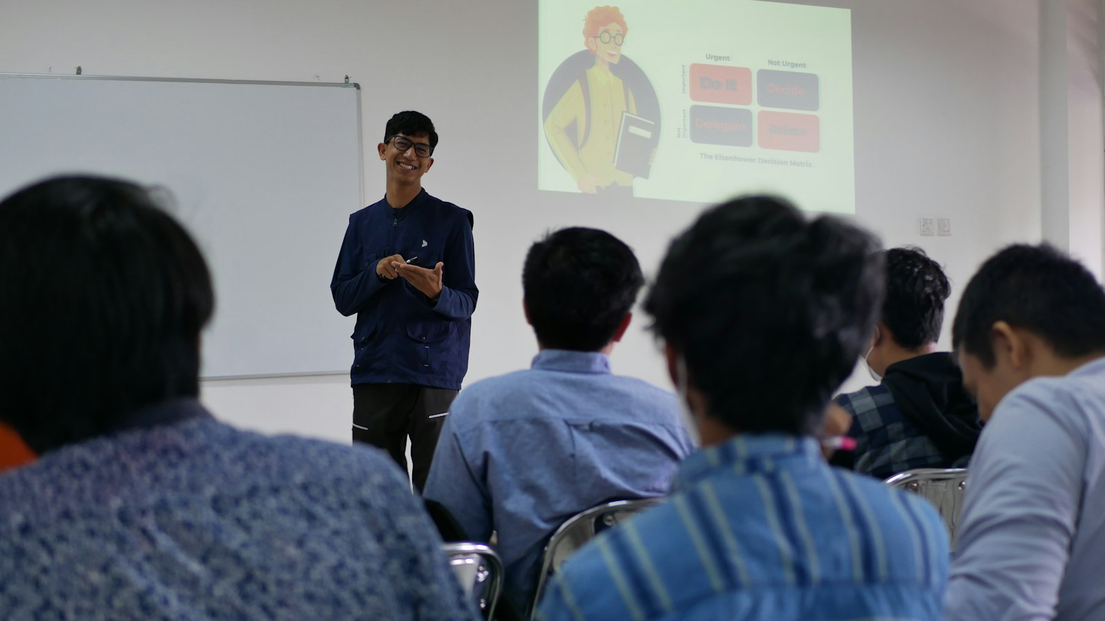 Evaluasi Pelatihan Karyawan dengan Model Kirkpatrick: 4 Level, Contoh Indikator, dan Cara Mengukurnya Pelatih berdiri di depan sekelompok peserta pelatihan