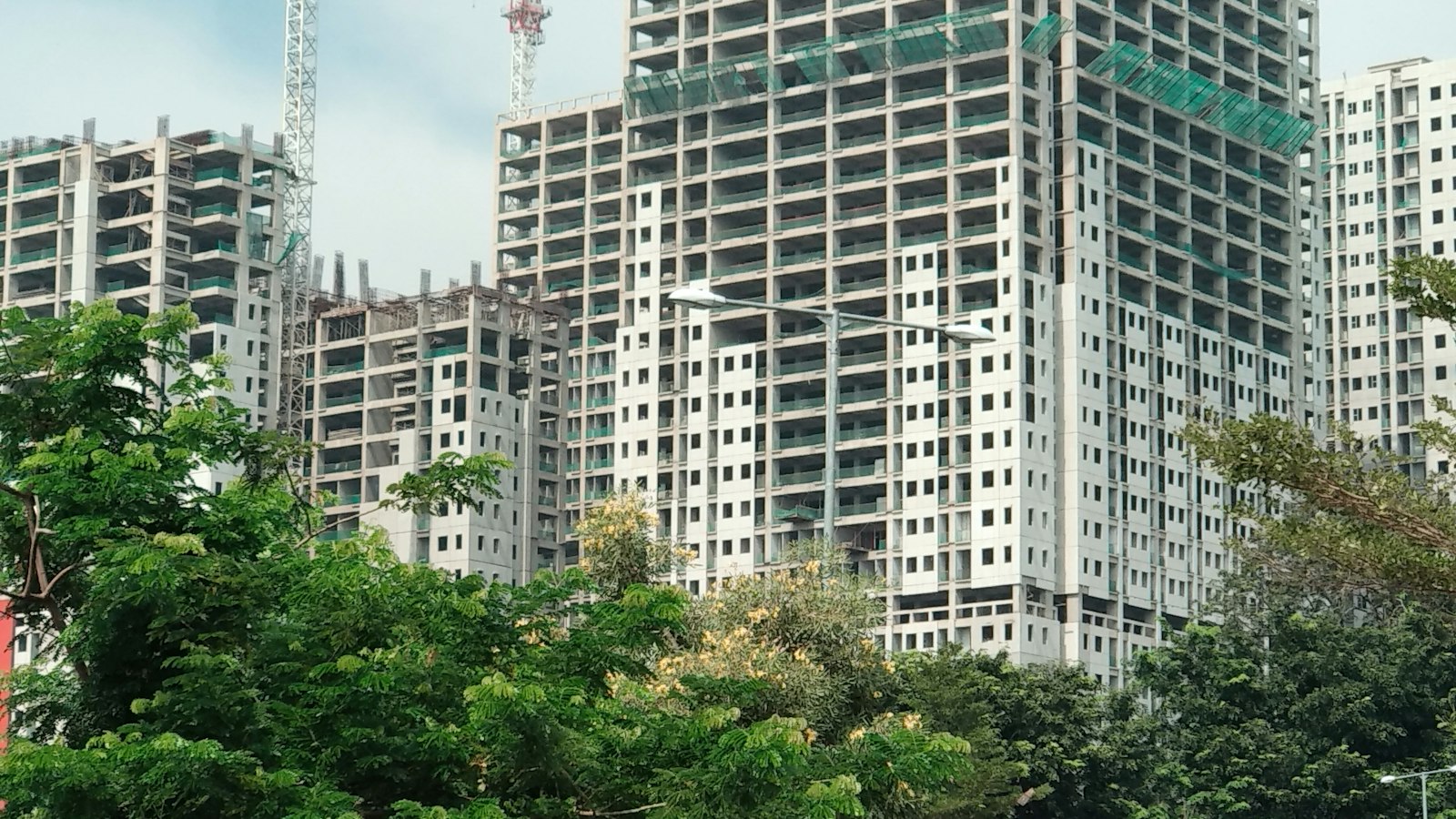 Rekomendasi Jasa Pembuatan Website di Bekasi: 6 Pilihan dan Cara Memilihnya Deretan apartemen bertingkat yang sedang dibangun di antara pepohonan hijau