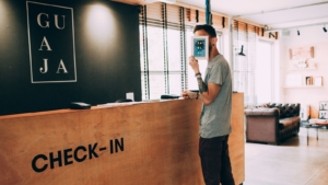 Tamu berdiri di meja check-in sambil memegang ponsel